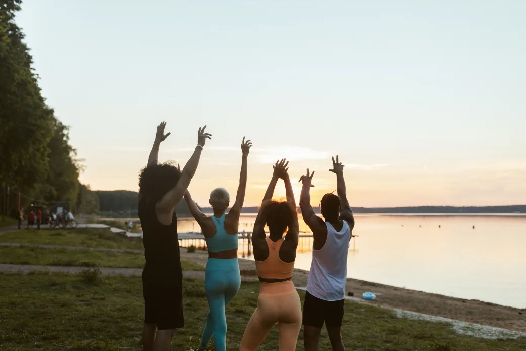 Group doing an outdoor workout session by the water at sunset
